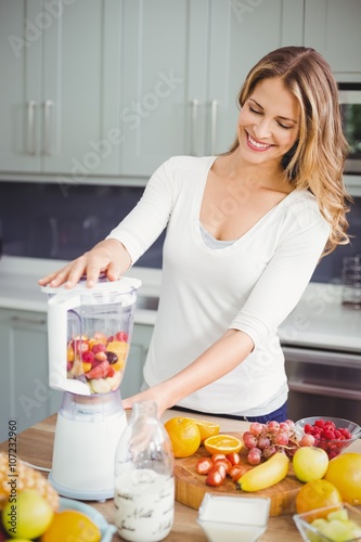 Smiling woman using juicer at table 