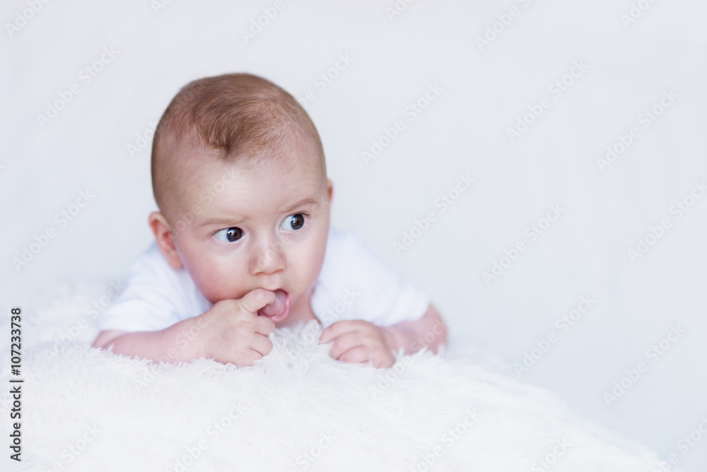 Newborn Baby Curiously Observing Environment on a Soft Blanket and Finger in Mouth Newborn Baby Curiously Observing Environment on a Soft Blanket and Finger in Mouth