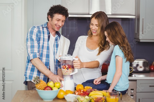 Parents and daughter preparing fruit juice 