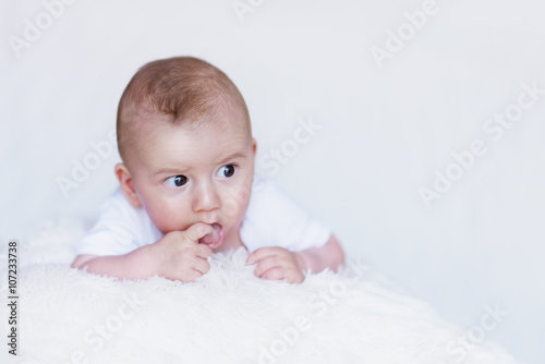 Newborn Baby Curiously Observing Environment on a Soft Blanket and Finger in Mouth