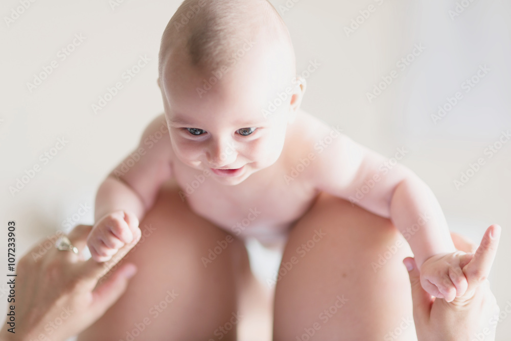 Newborn Baby Looking At Mother and Smiling Happily Naked, Holding Fingers with Fist Newborn Baby Looking At Mother and Smiling Happily Naked, Holding Fingers with Fist