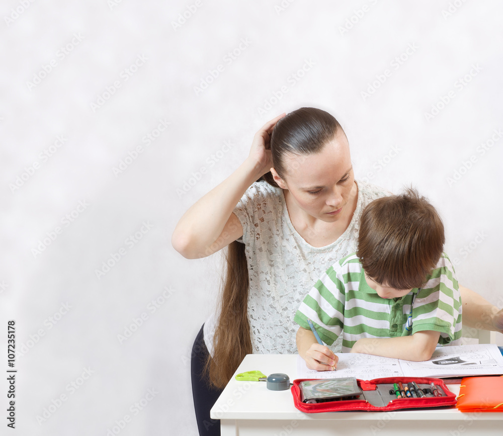 The mother checks the homework of her son The mother checks the homework of her son