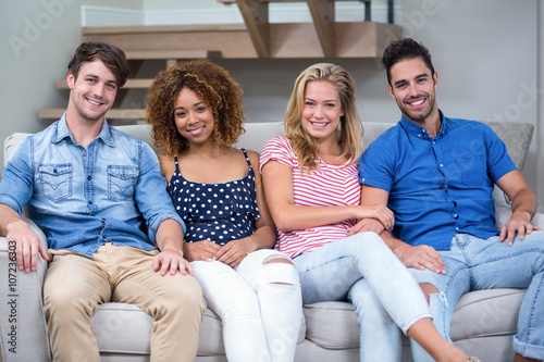 Young friends smiling while sitting on sofa