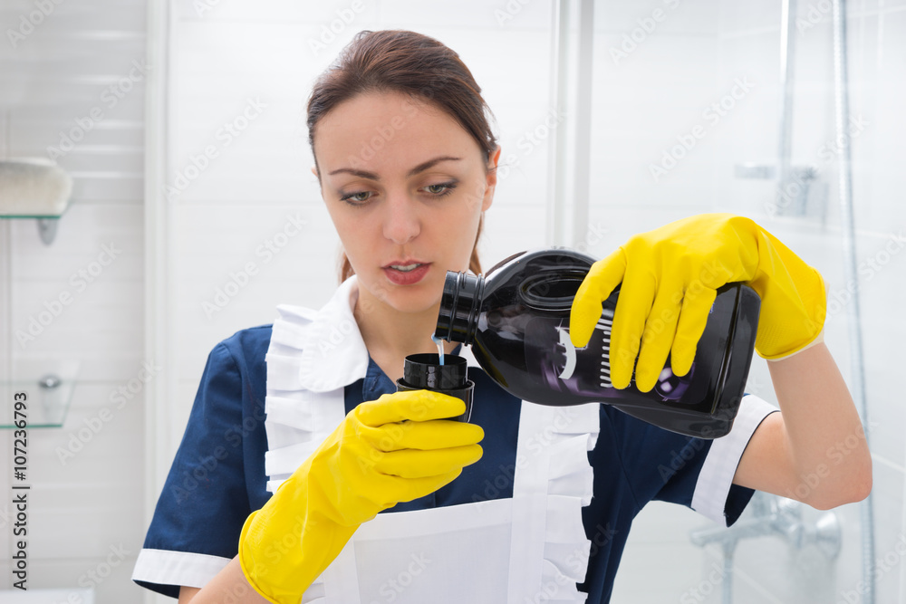 Housekeeper measuring out detergent from a bottle Housekeeper measuring out detergent from a bottle