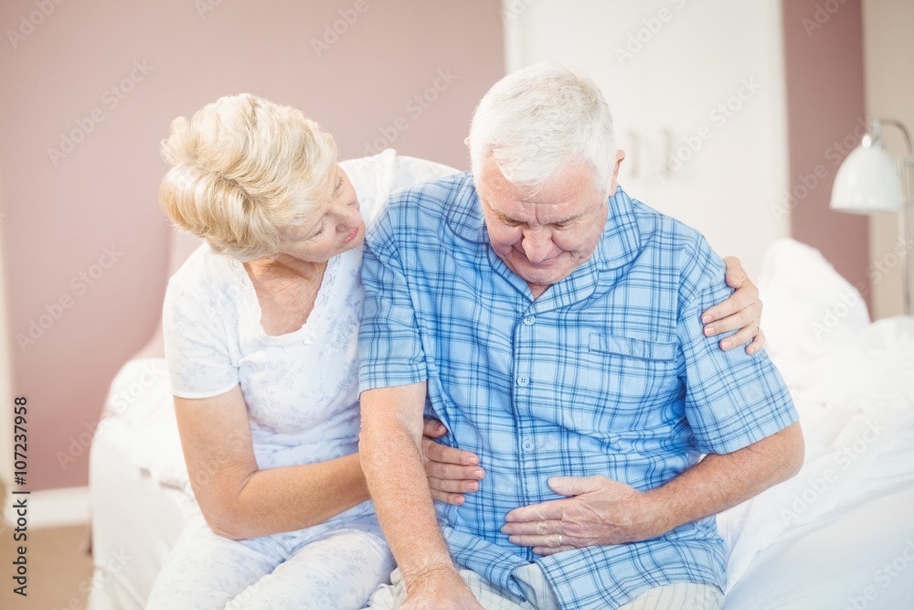 Wife comforting senior husband suffering from stomach pain Wife comforting senior husband suffering from stomach pain