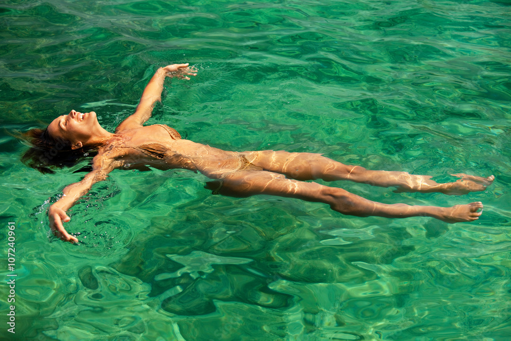 corps de femme dans l'eau cristalline qui fait la planche 
