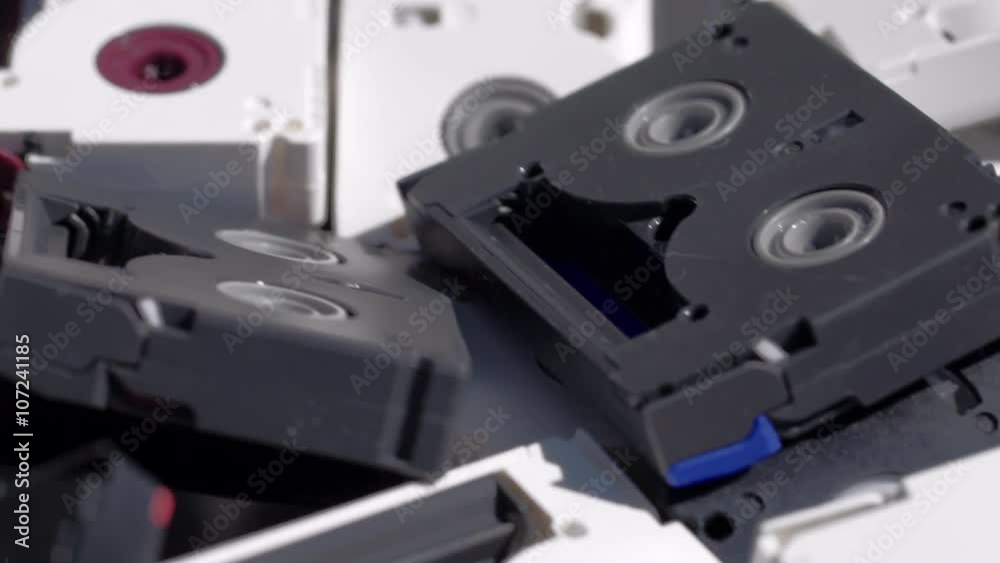 Tilt over a pile of digital video tapes.  Macro shot, with shallow depth of field and racking focus.  Recorded in 4K.