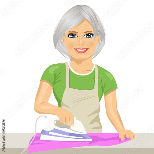 Happy senior woman ironing clothes. Housework