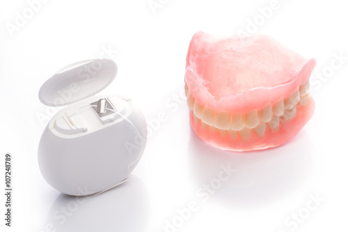 Teeth model with dental floss on white background
