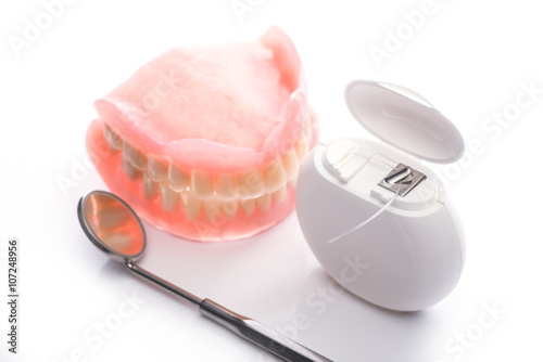 Teeth model with dental floss and mouth mirror on white background