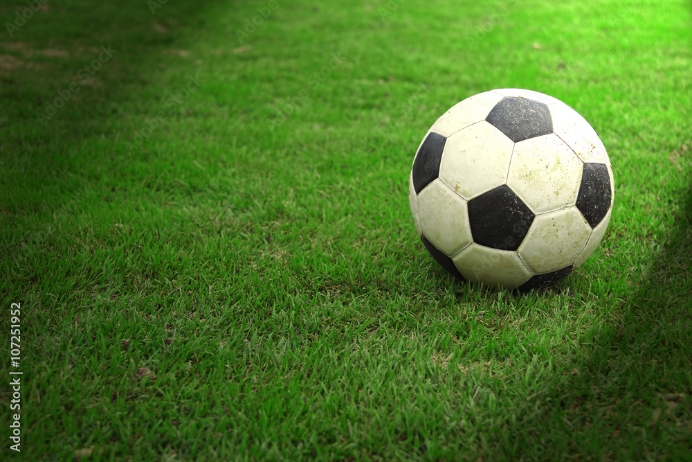 Football on green grass with spot light