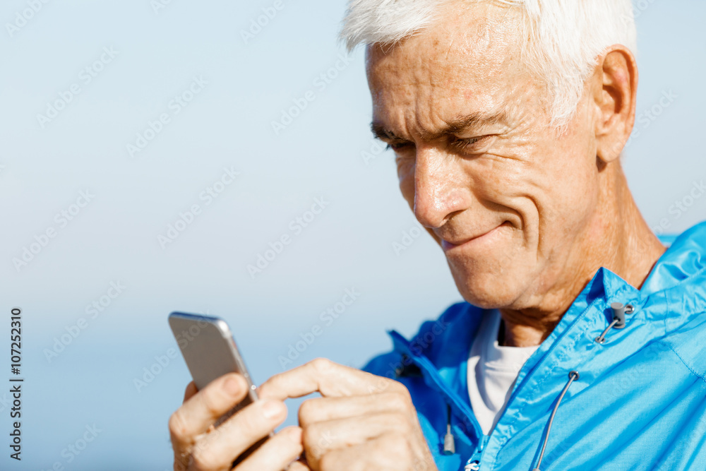 Male runner with his mobile smart phone standing outdoors Male runner with his mobile smart phone standing outdoors