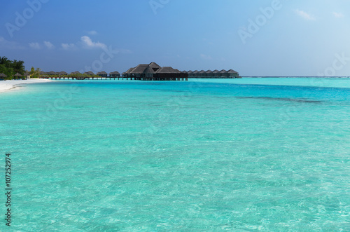 bungalow huts in sea water on exotic resort beach