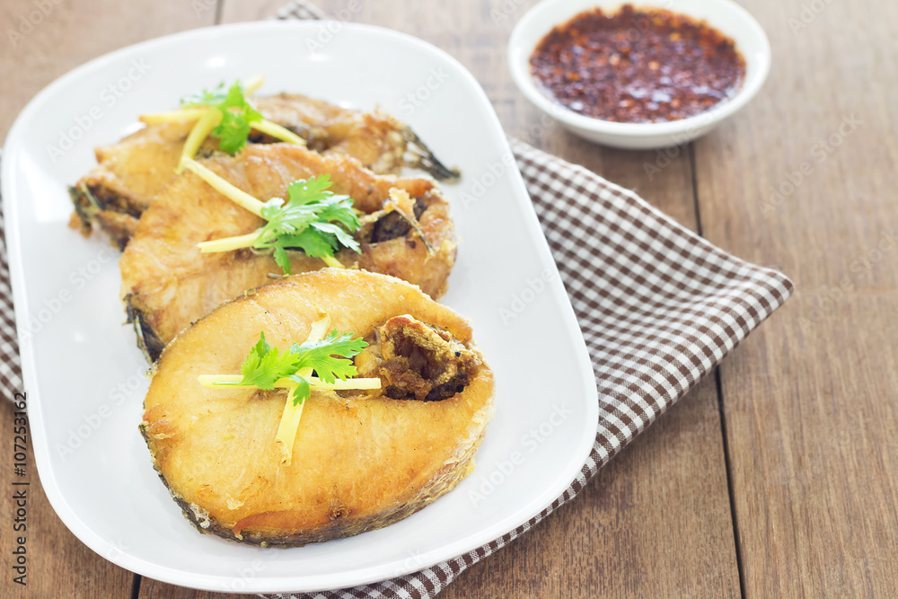 Fried fish with chili sauce on a white plate, Wooden background Fried fish with chili sauce on a white plate, Wooden background