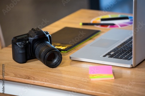 Camera, sticky notes, graphics tablet and laptop at desk
