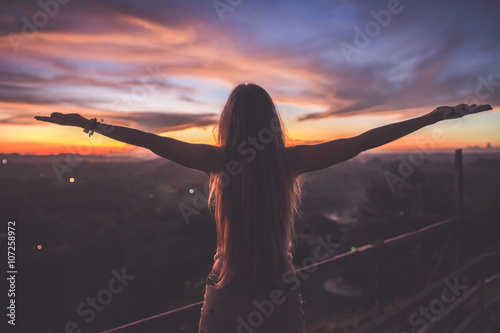 Silhouette of the woman spreading arms and standing high on the viewpoint with breathtaking view over fields in sunset light.Chocolate Hills, Bohol Island, Philippines.
