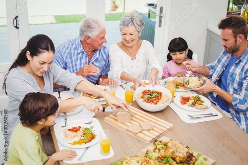 Smiling multi generation family having food