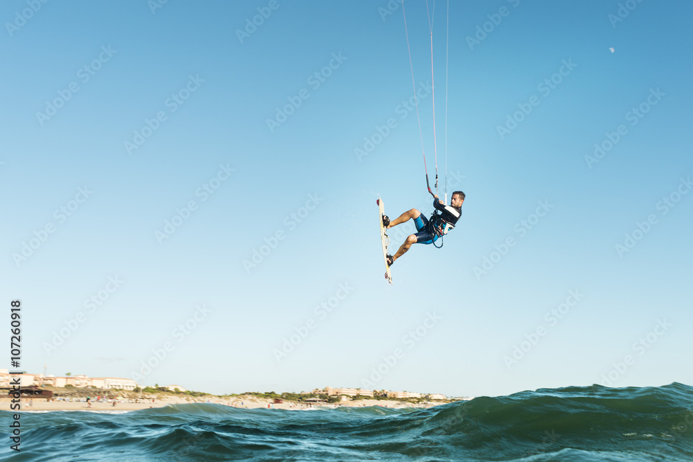 Fototapeta premium Surfer jumping in front of the beach