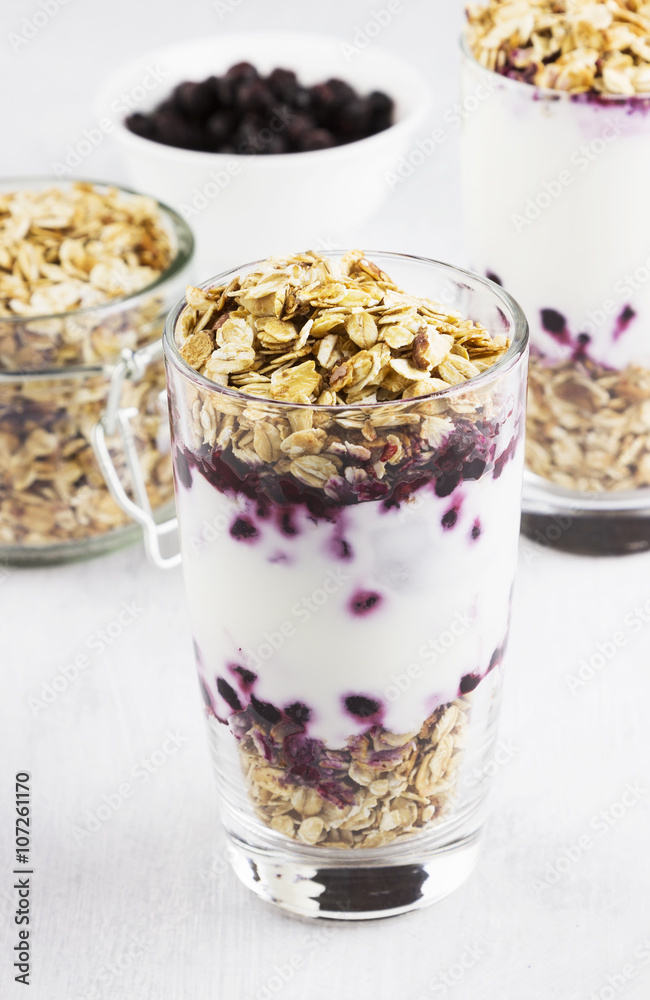 Useful dessert of granola, yogurt and blueberry in glass on a wh Useful dessert of granola, yogurt and blueberry in glass on a wh