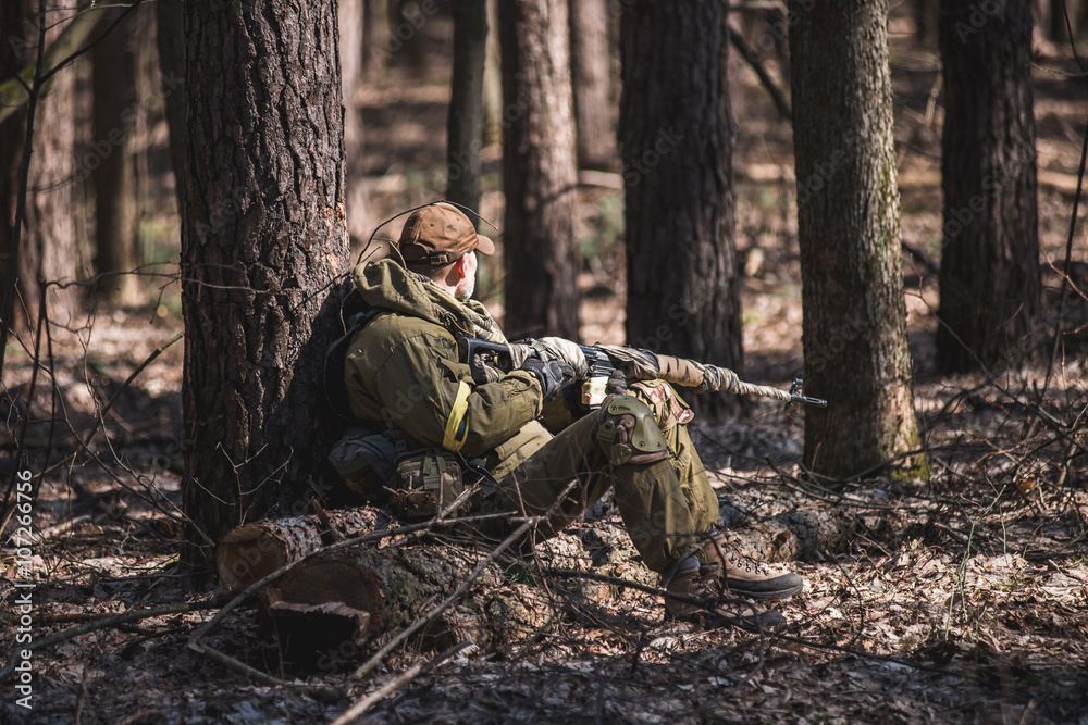 Soldier rest in forest/Soldier in military uniform with rifle sat down to rest in the forest
