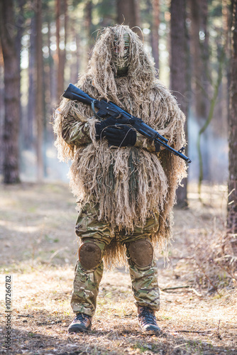 Sniper in camouflaged suit with rifle/Soldier in camouflaged sniper suit  standing in forest with rifle in hands.Selective focus.