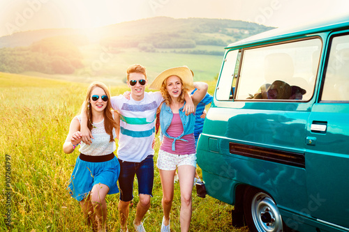 Young frieds with campervan, green nature and blue sky © Halfpoint