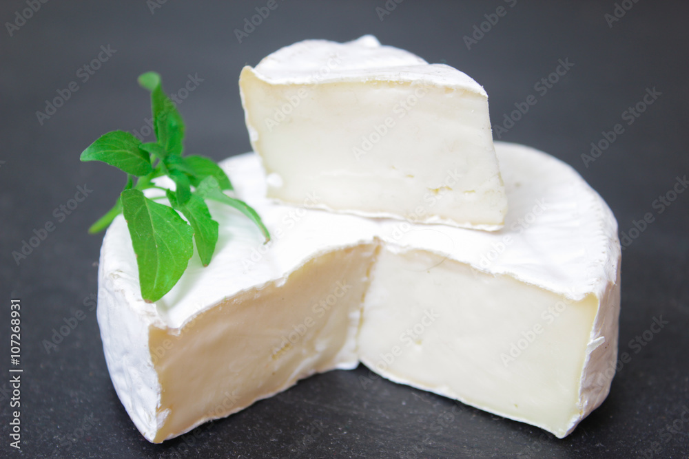Brie cheese. Camembert cheese. Fresh Brie or Camembert cheese with basil leaves. Italian, French and Mediterranean ingredients.