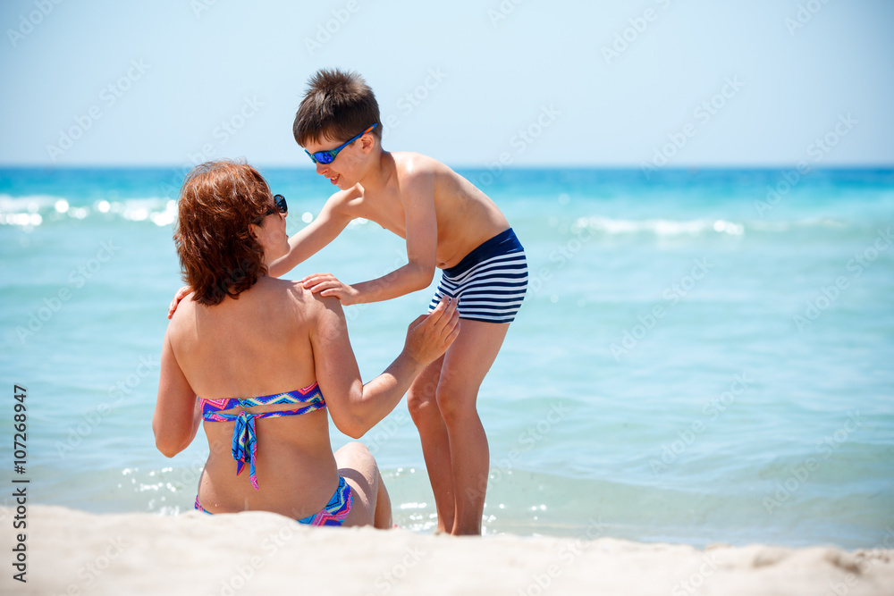 Naklejka premium Back view of mother and son enjoying tropical beach vacation