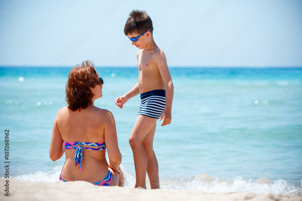 Back view of mother and son enjoying tropical beach vacation