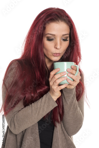 Junge Frau pustet in ihre Kaffeetasse