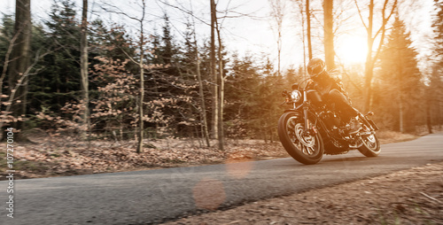 Man seat on the motorcycle on the forest road. photo