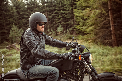 Man seat on the motorcycle on the forest road.