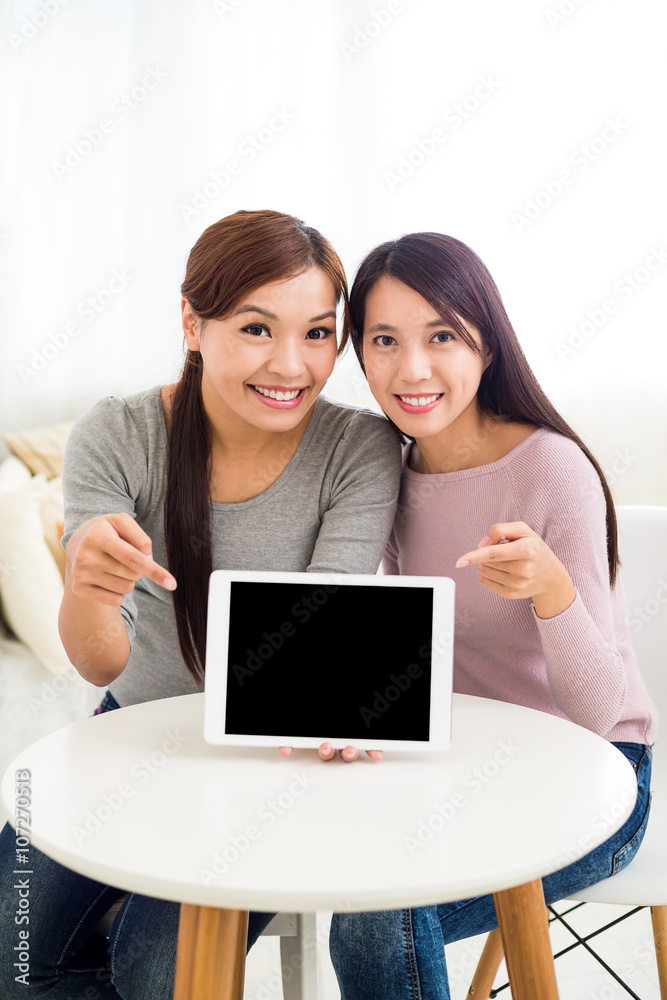 Two woman with finger pointing to the blank screen of tablet pc Two woman with finger pointing to the blank screen of tablet pc