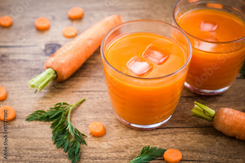 Carrot juice and carrot segments on a wooden background