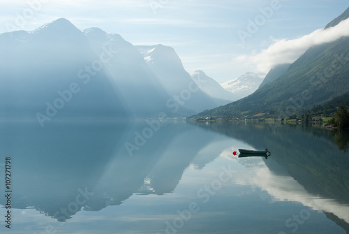 Landscape with mountains reflecting in the water and small boat, Norway