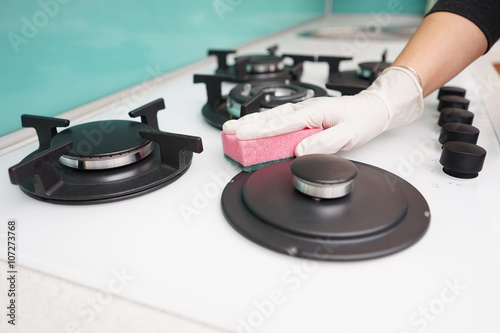 closeup of female hand cleaning the gas stove in kitchen