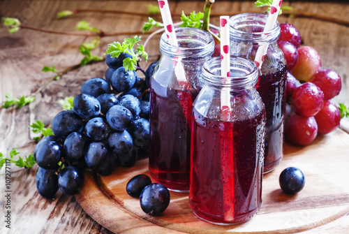 Fotografia Juice from dark grapes in small glass bottles, selective focus