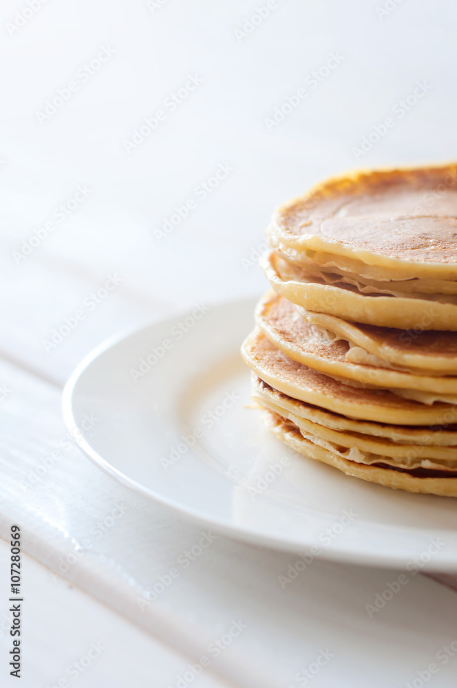Light breakfast. Fresh pancakes on white plate in morning light Light breakfast. Fresh pancakes on white plate in morning light