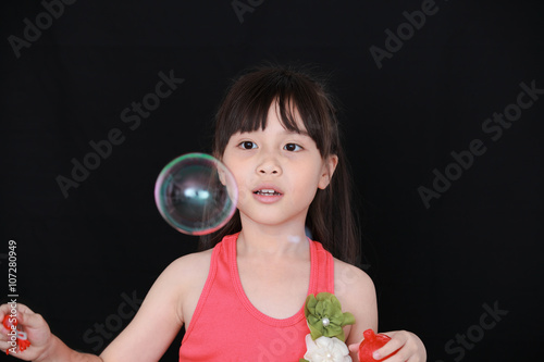 Happy girl play with soap bubbles isolated black background