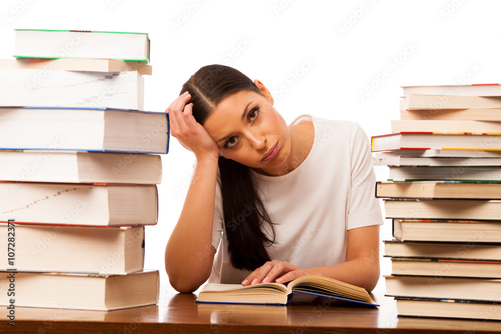 Sick and tired woman reading behind the table between two pile o Sick and tired woman reading behind the table between two pile o