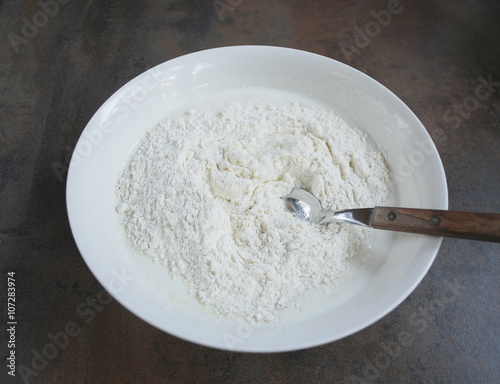 Dough for cheesecakes, spoon are in a white dish. Preparation for cooking. 