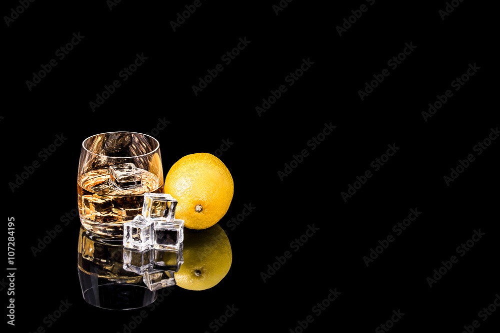 Glass whiskey with ice and lemon on black background