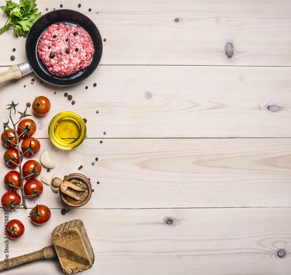 cooking burgers, ground beef with herbs and cherry tomatoes on a branch border ,place for text on wooden rustic background top view cooking burgers, ground beef with herbs and cherry tomatoes on a branch border ,place for text on wooden rustic background top view
