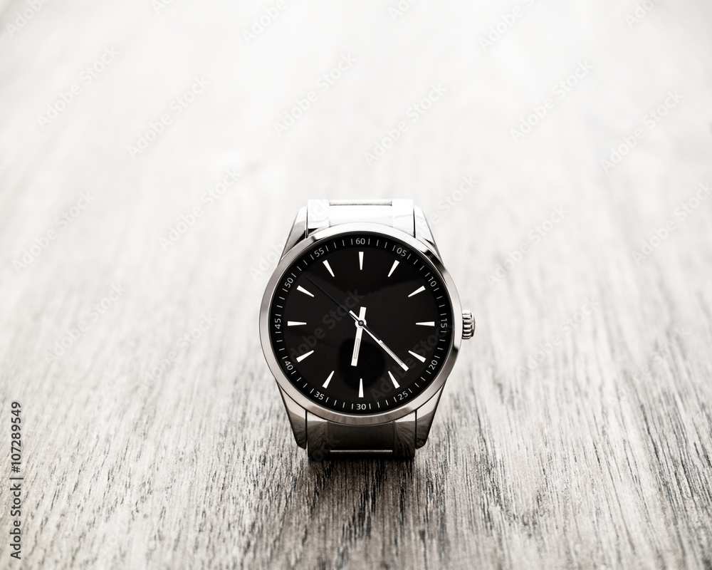 Silver reflective wrist watch with black dial on wood surface Silver reflective wrist watch with black dial on wood surface