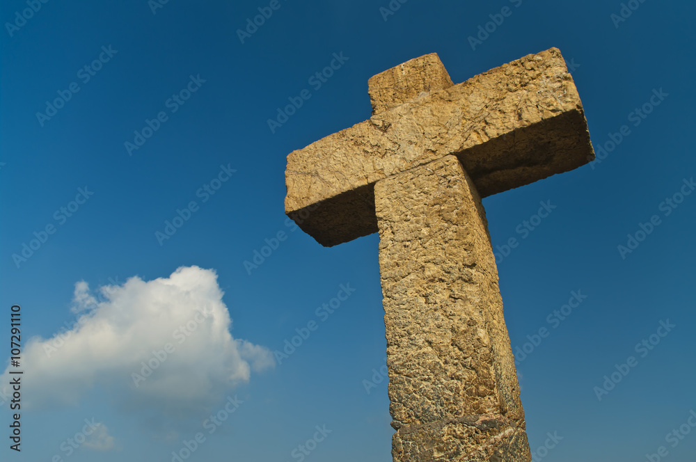 stone cross against blue sky on sunny day