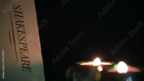 Candles Flicker next to a Shakespeare Book in the Dark photo