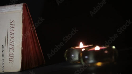 Candles Flicker next to a Shakespeare Book in the Dark photo