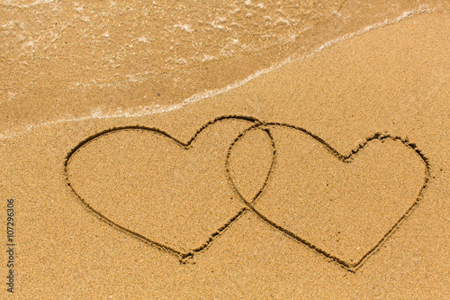 Two hearts drawn on the sand of a sea beach.