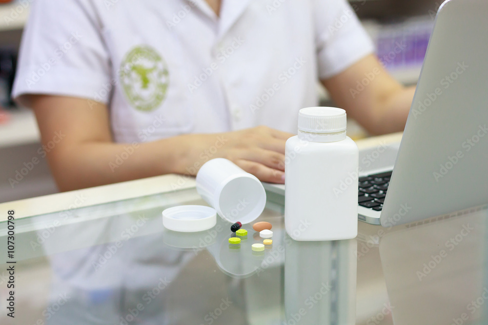 Pharmacist with laptop computer and medication in the pharmacy Pharmacist with laptop computer and medication in the pharmacy