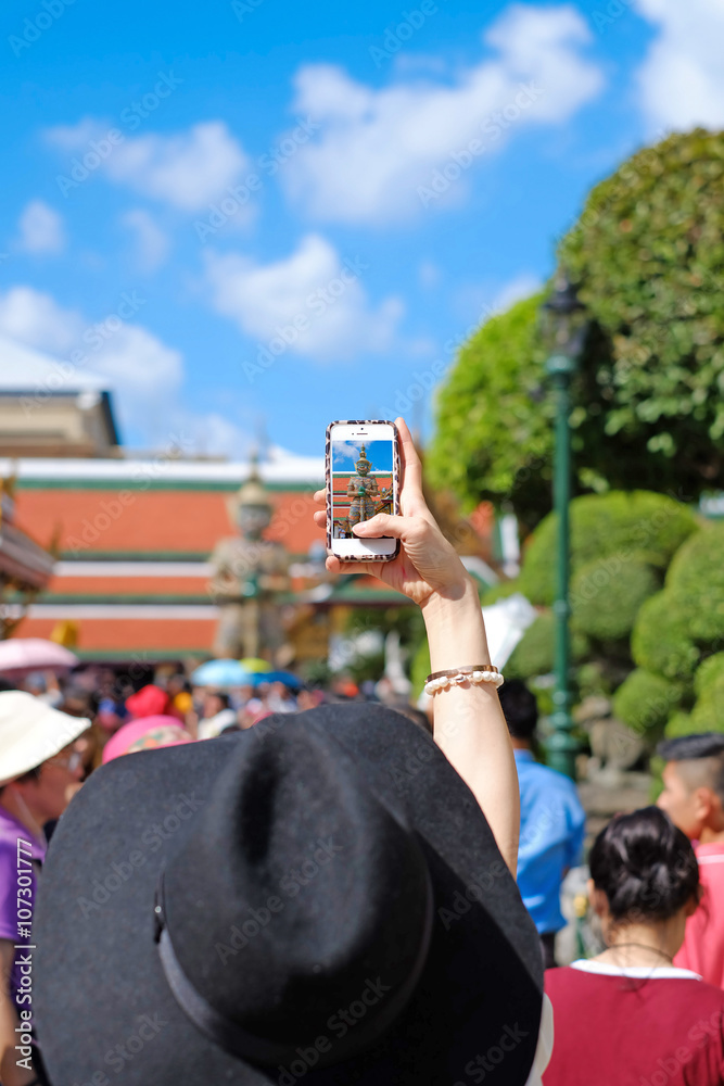 Obraz premium Woman taking picture a Giant in Thailand and Blue sky.